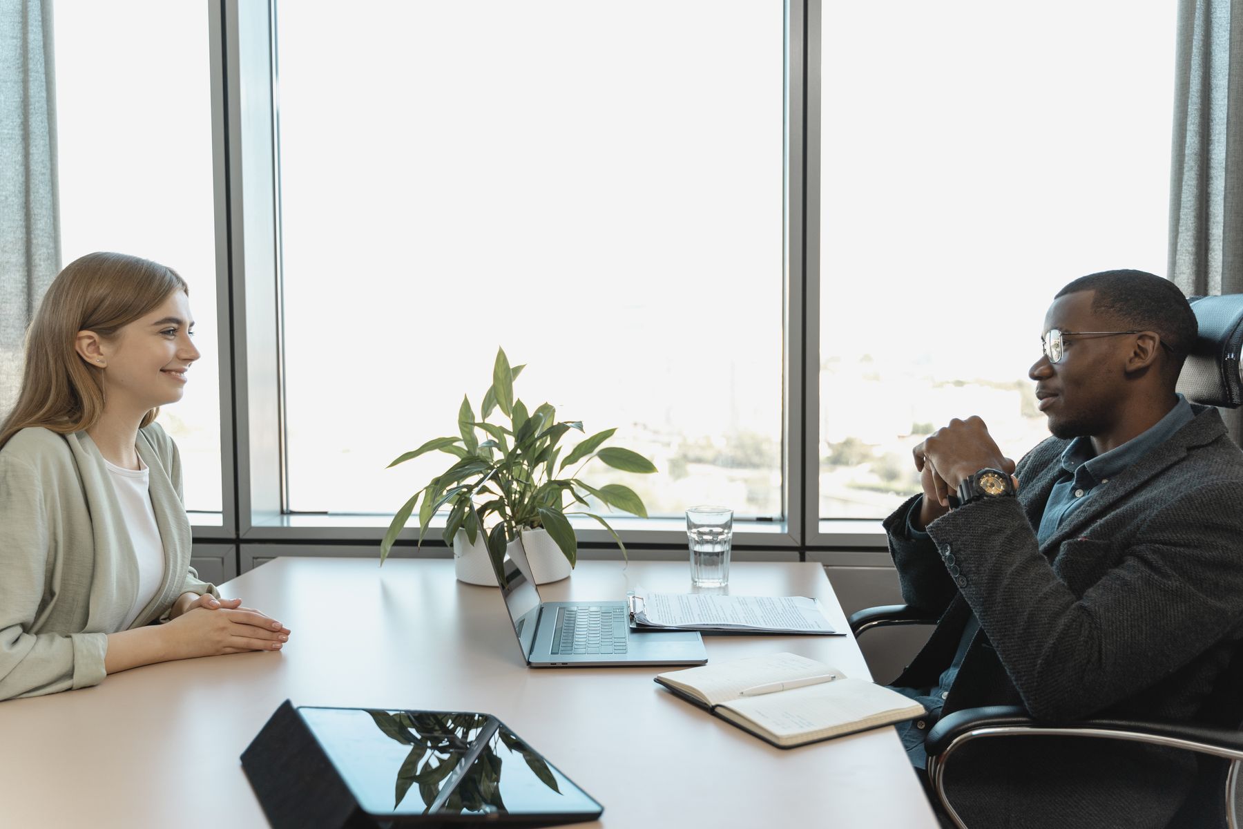 Two professionals discussing a job opportunity across a desk in a bright office